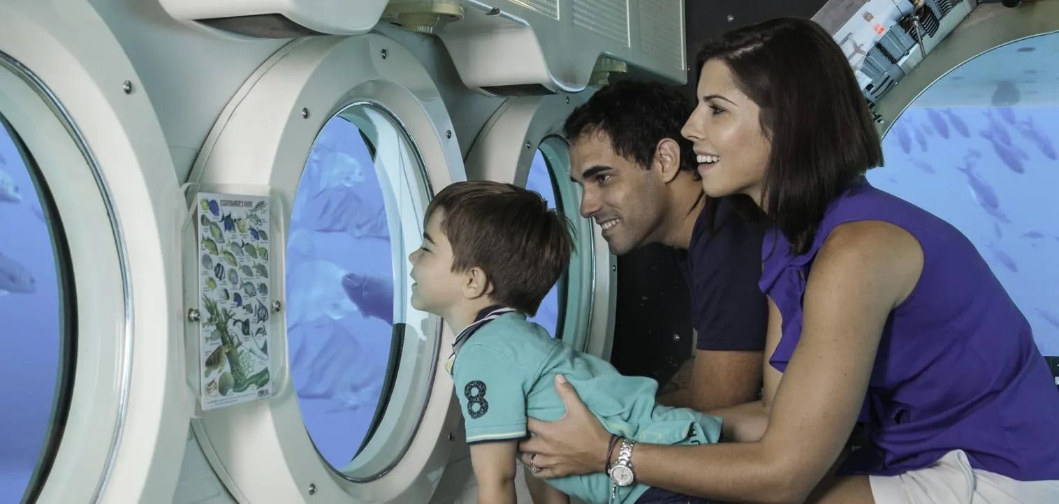 Family looking out of the submarine's viewports at the reef