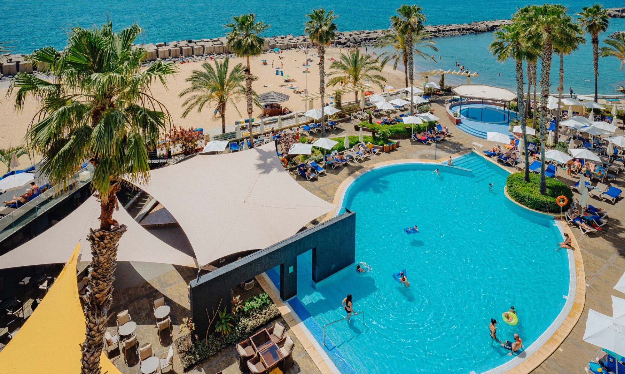Pools, palms and the beach seen from above