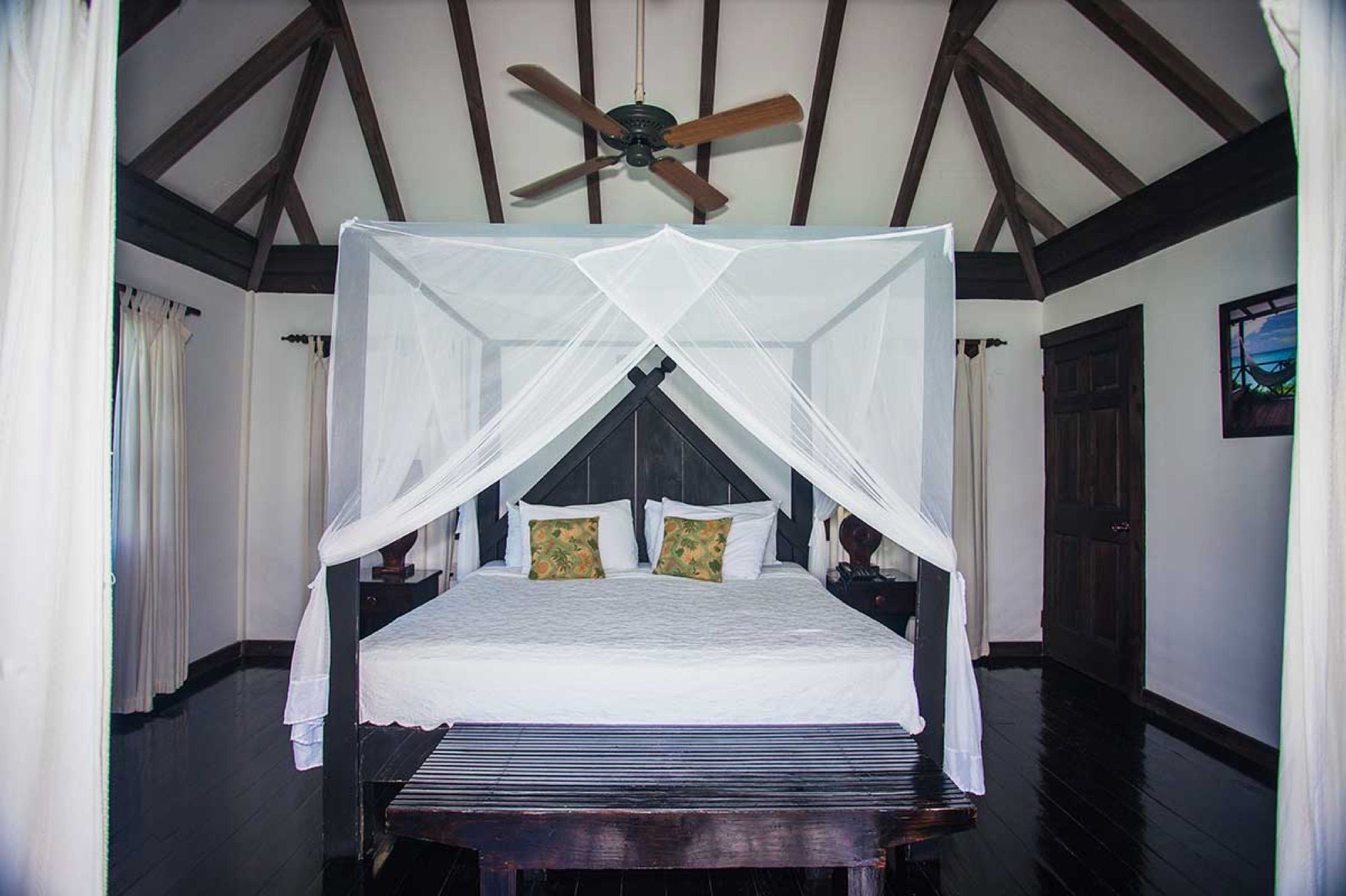 Four-poster bed with mosquito net in a wooden cottage