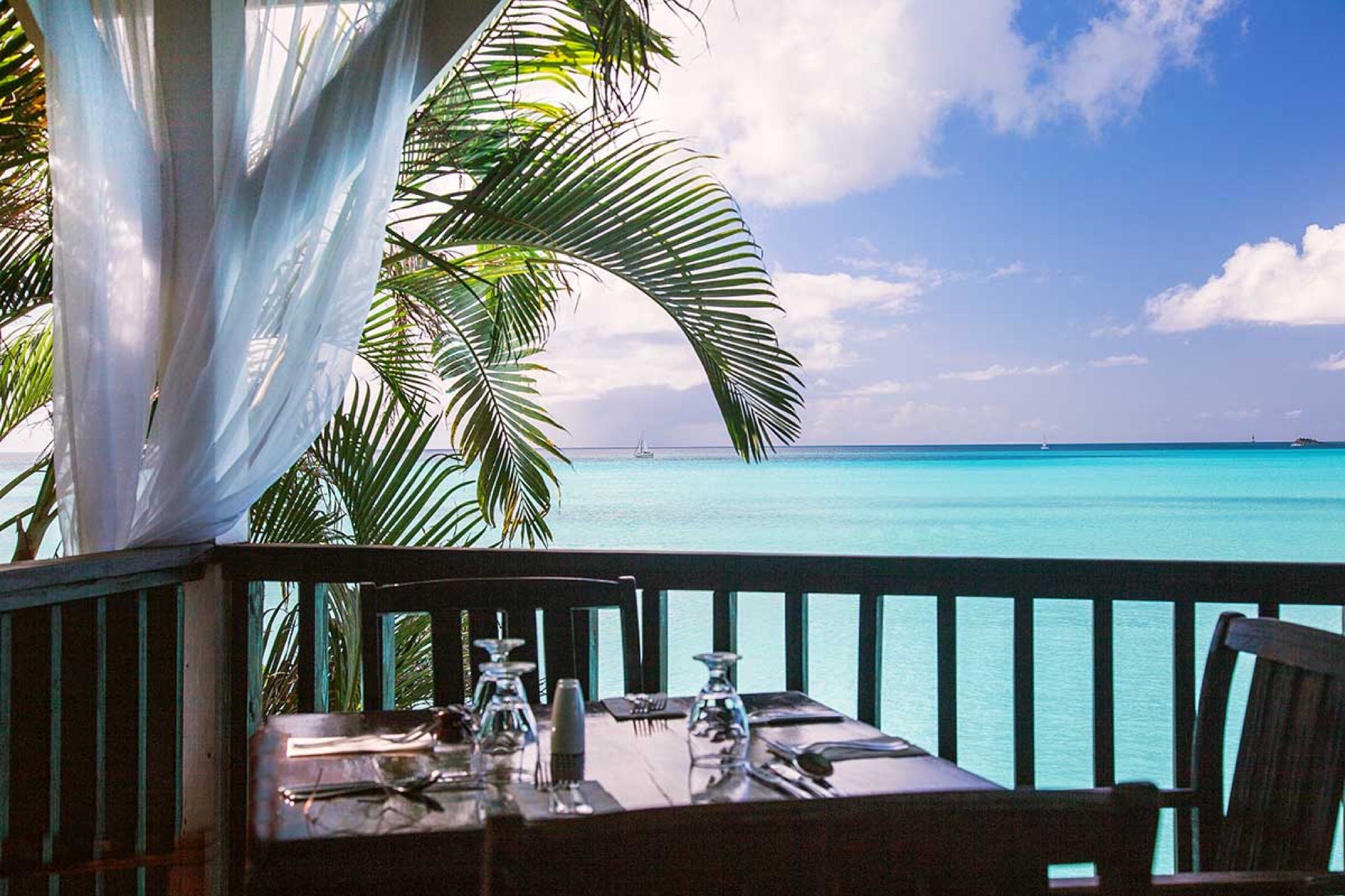 Table set on the open-air restaurant terrace above the sea