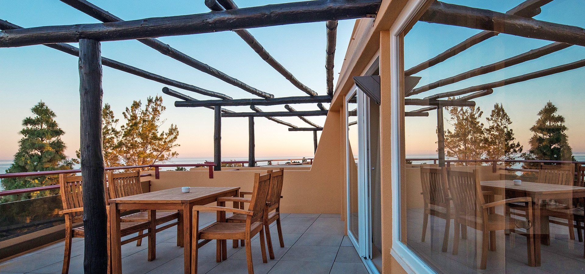 Terrace with table and chairs looking out to sea at sunset