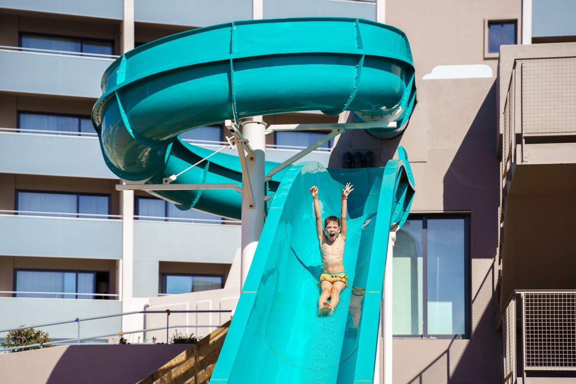 Child sliding down a turquoise water slide at Jupiter Albufeira
