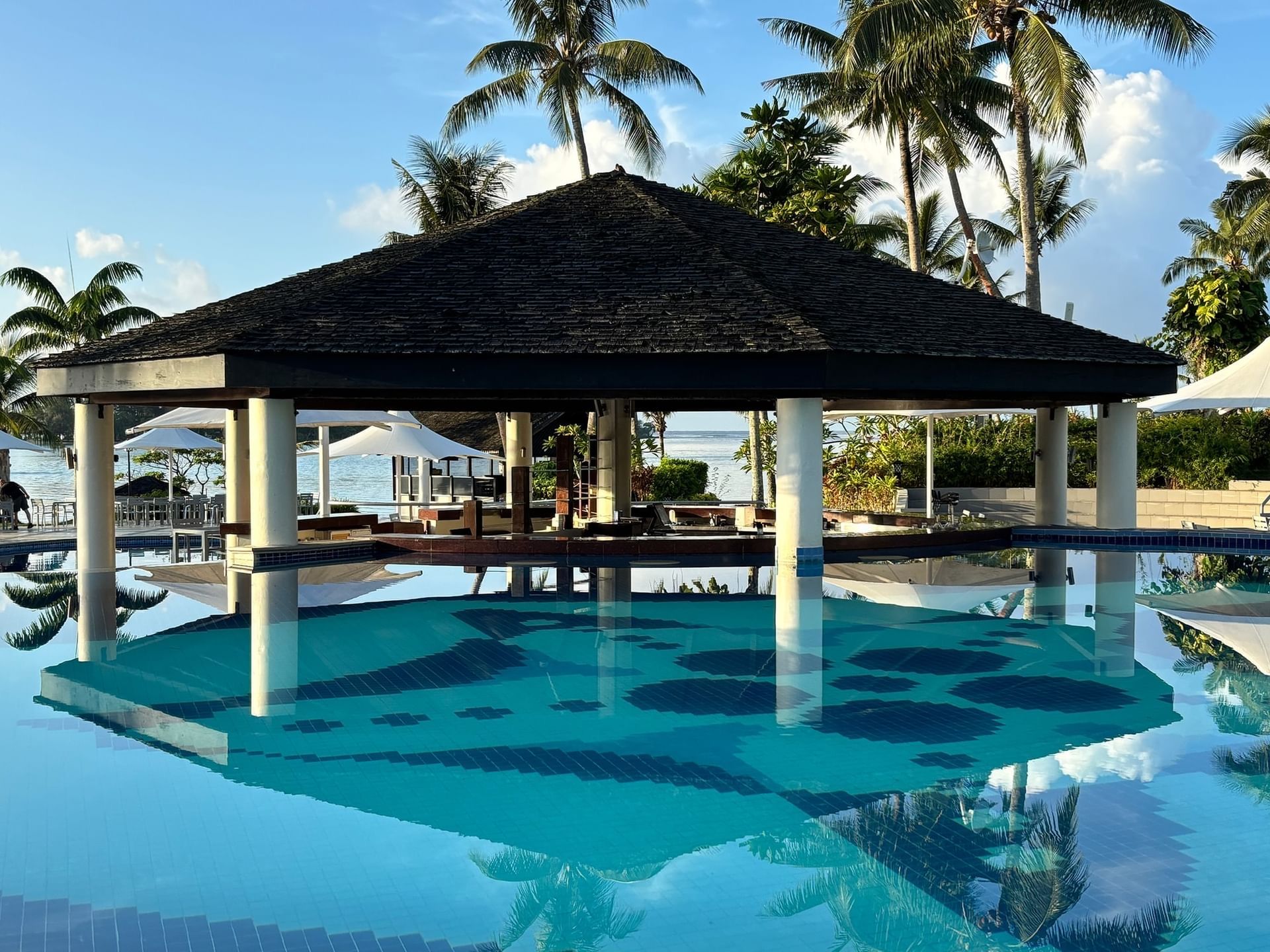 Swim-up pool bar under a thatched pavilion