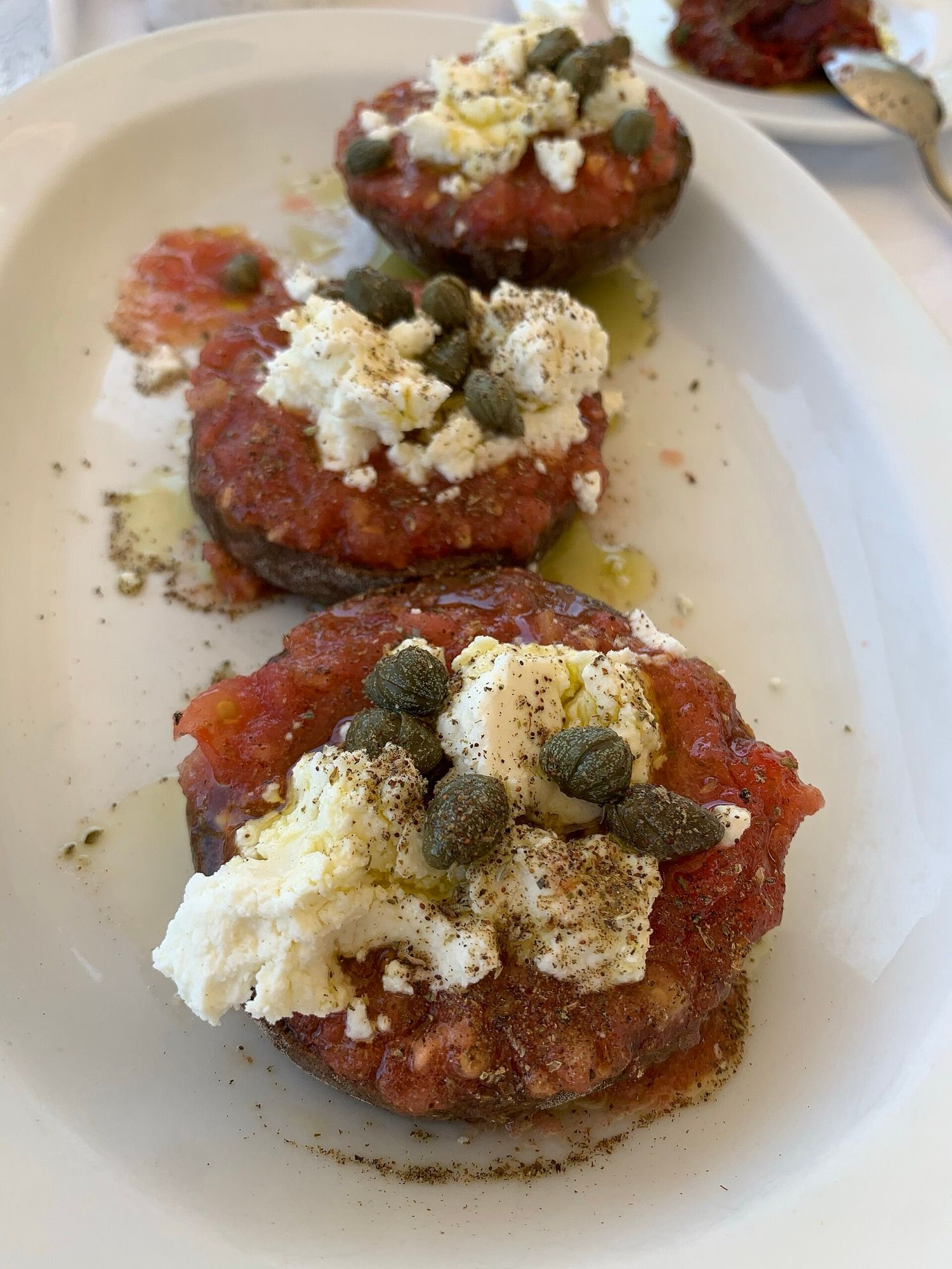 Dakos: barley rusk topped with tomato, mizithra cheese and capers
